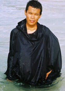 Asian local guide wading in sun poncho